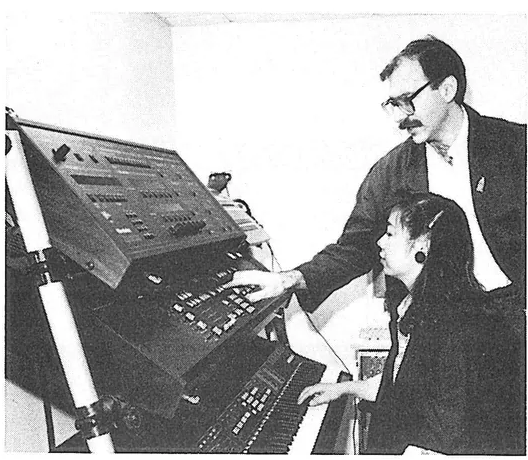 Black and white photograph showing David Mash demonstrating a K250 synthesizer to student Angela Ng